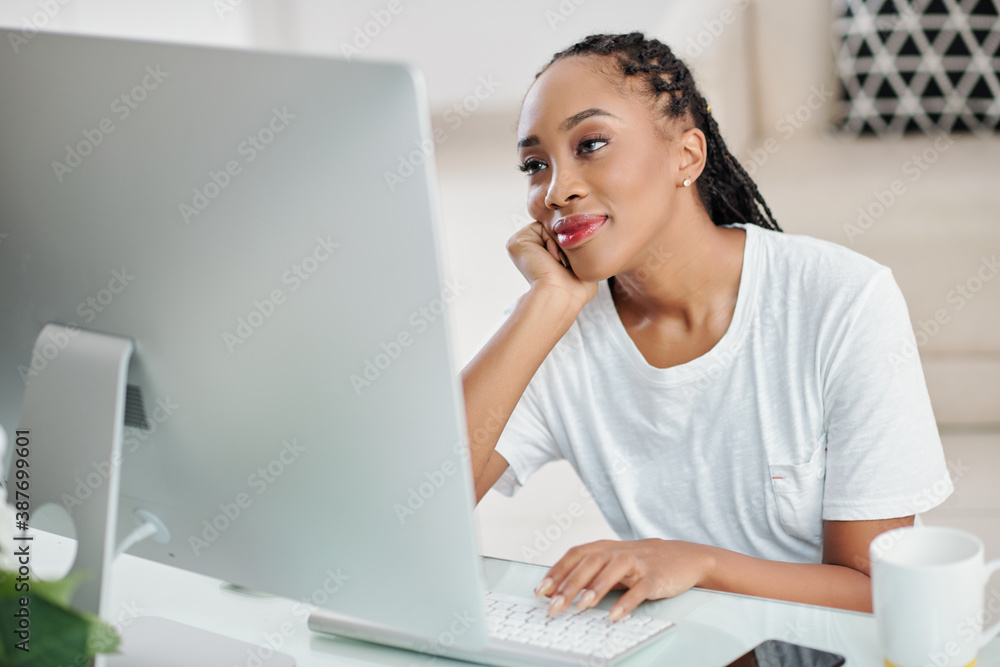 Smiling pretty young Black woman watching romantic movie on screen of computer Smiling pretty young Black woman watching romantic movie on screen of computer