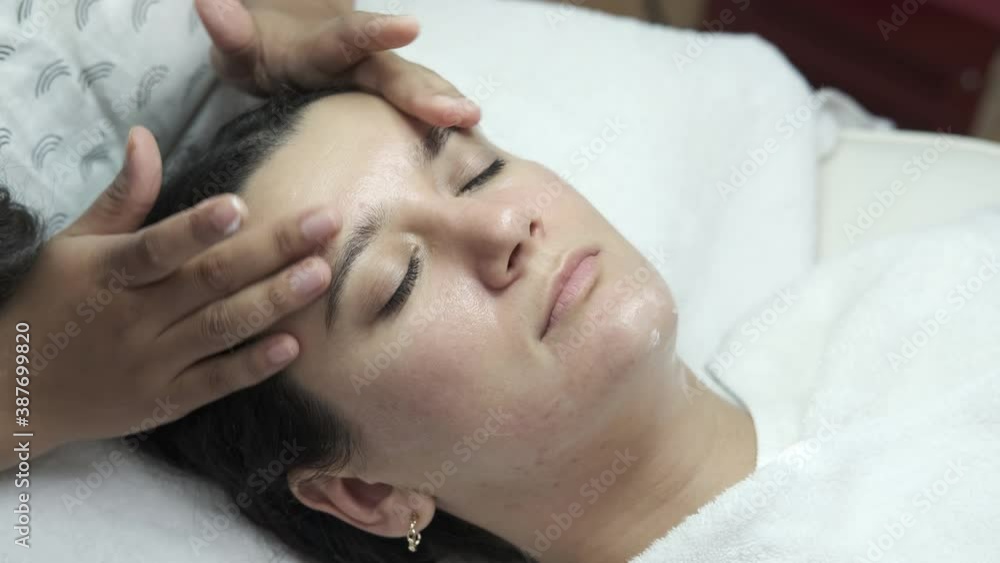 Relaxed woman lying in salon and having deep cleansing nourishing facial treatment. Beautician applying cream and doing massage to client face. Healthcare, wellness and medicine Relaxed woman lying in salon and having deep cleansing nourishing facial treatment. Beautician applying cream and doing massage to client face. Healthcare, wellness and medicine