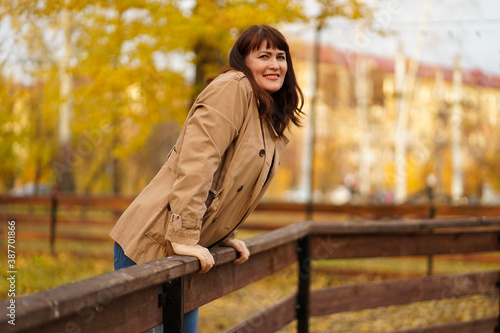happy woman in autumn Park stands near a wooden fence