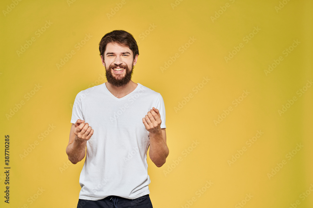 Man gesturing with hands emotions lifestyle white t-shirt yellow isolated background Man gesturing with hands emotions lifestyle white t-shirt yellow isolated background