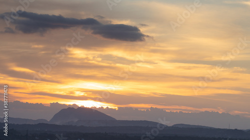 Silhouette of hills against beautiful golden hour light with wide angle and beautiful clouds formation and a glimpse of blue sky
