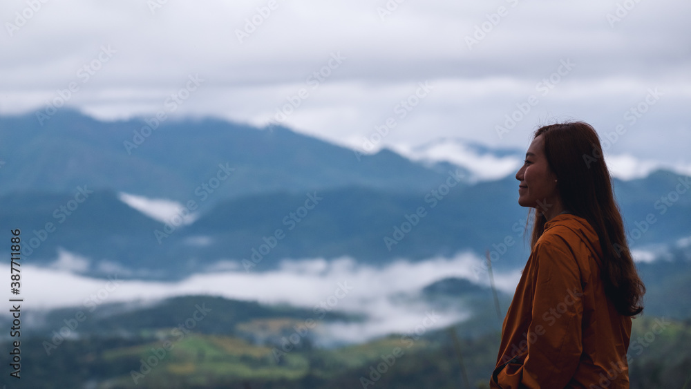 Portrait image of a female traveler looking at a beautiful foggy mountain and nature view