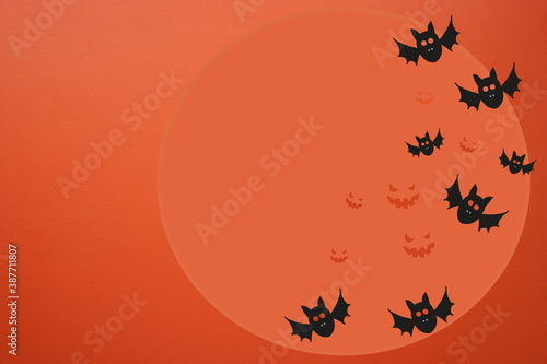 Orange background for Halloween. Drawing of bats and a scary smile on the moon