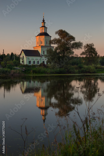 Village church with pond at sunset with reflection