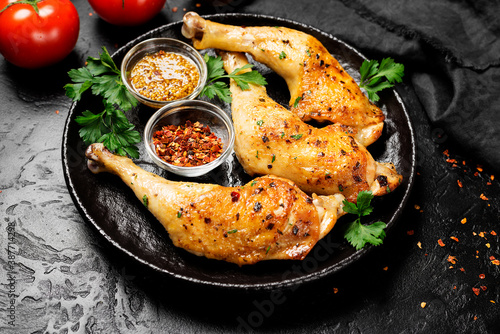 Grilled chicken legs with spices on black background