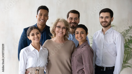 Portrait of smiling multiracial businesspeople pose together at workplace show leadership. Happy diverse multiethnic employees with middle-aged female boss demonstrated unity and support in office.