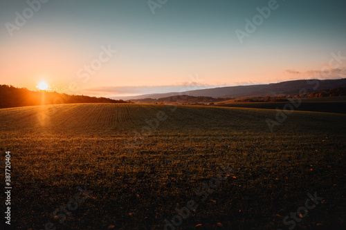 Colorful orange sunrise with grass fields and landscape nature. Morning sun creating shadow of the curvy and hilly nature. Harz National Park  Harz Mountains in Germany