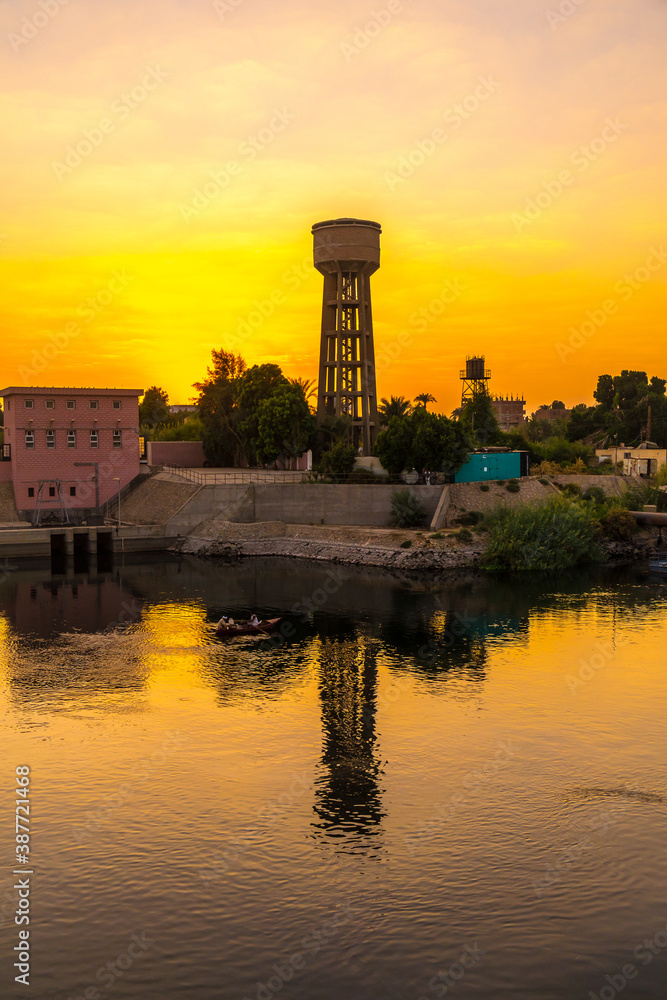 A town near the river at sunset on the Nile river cruise. Egypt. Sailing from Luxor to Aswan, view of traditional villages and the nature of the Nile river