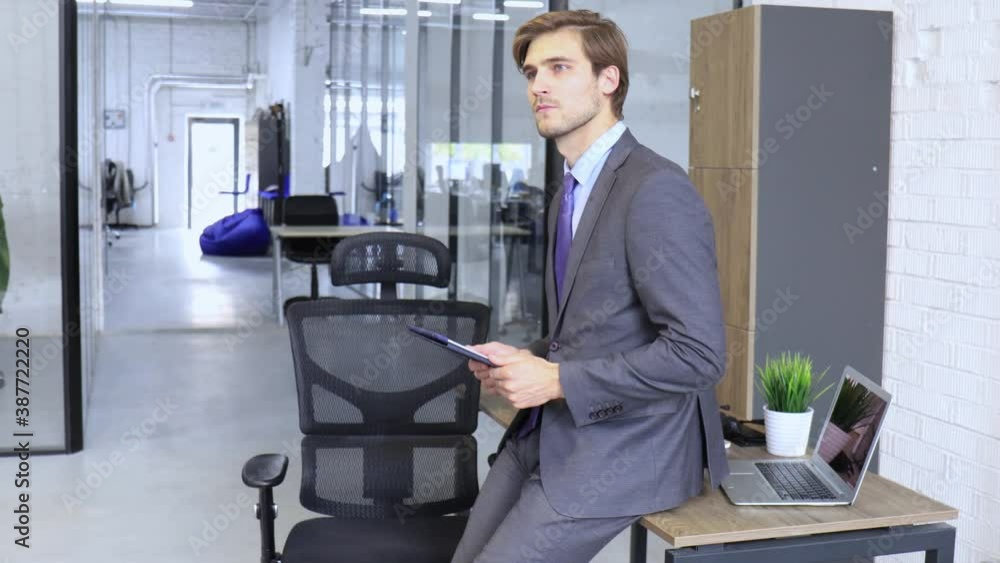 Caucasian man working in a casual office, standing and using a digital tablet Caucasian man working in a casual office, standing and using a digital tablet