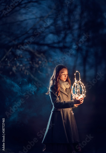 Girl with lantern in the night forest