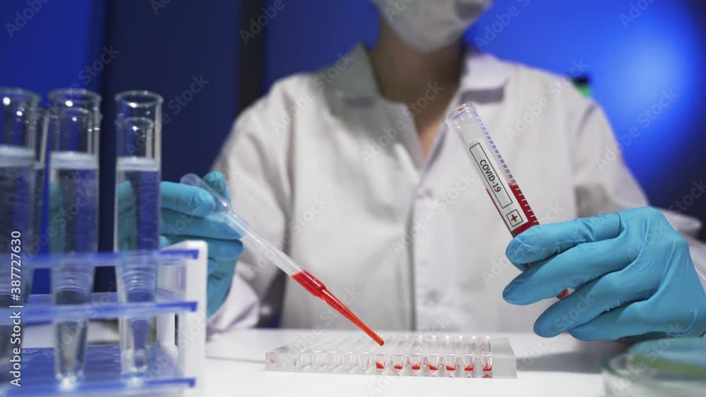 A doctor in a white coat and mask makes an immunological test for coronavirus. A doctor in a white coat and mask makes an immunological test for coronavirus.