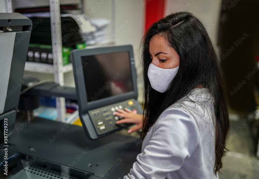 Beautiful woman with face mask making copies with copy machine Beautiful woman with face mask making copies with copy machine