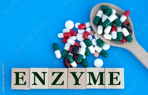 ENZYME word on cubes on a blue background with a spoon with pills photo