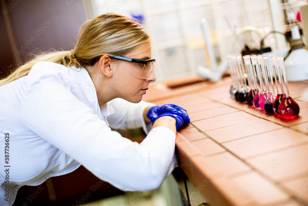 Female scientist in white lab coat analyzing liquid samples the biomedical lab Female scientist in white lab coat analyzing liquid samples the biomedical lab