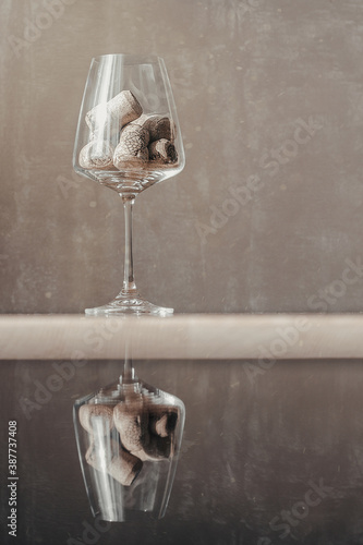 Image of wine corks in a transparent glass on a table in the dust of the sun with reflection
