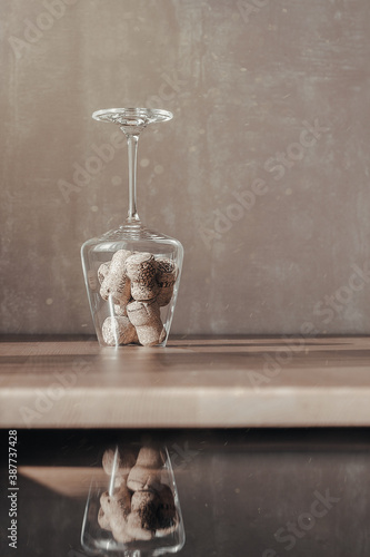 Image of wine corks in a transparent glass on a table in the dust of the sun with reflection