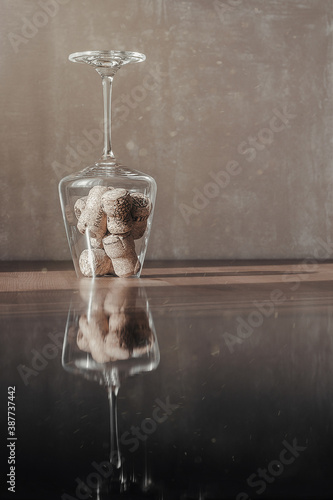 Image of wine corks in a transparent glass on a table in the dust of the sun with reflection