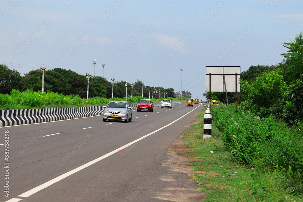 red cars and white cars with yellow auto on the india highway