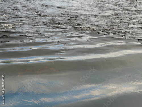 Ripple on the gray water surface  Wave in the sea and the reflection of the blue sky and white cloud