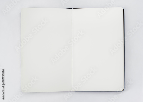 Unfold open notebook, book with blank white pages on light backdrop. Sketchbook photo