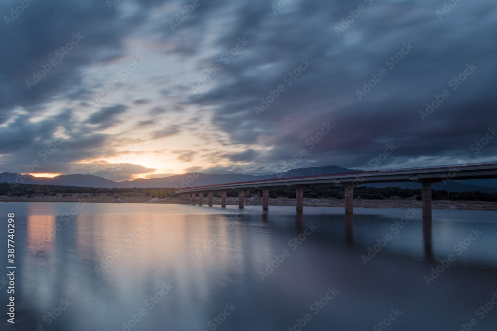 Fototapeta premium Puente sobre un lago con grafitis y atardecer de fondo