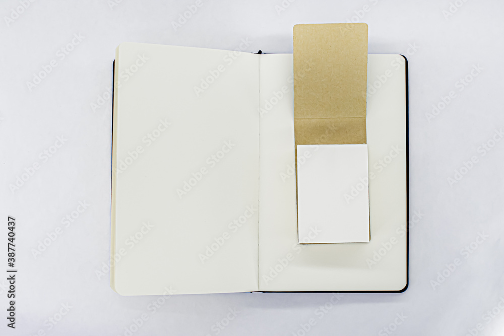 Unfold black notebook and open notepad with blank light beige pages. Top view. White background Unfold black notebook and open notepad with blank light beige pages. Top view. White background