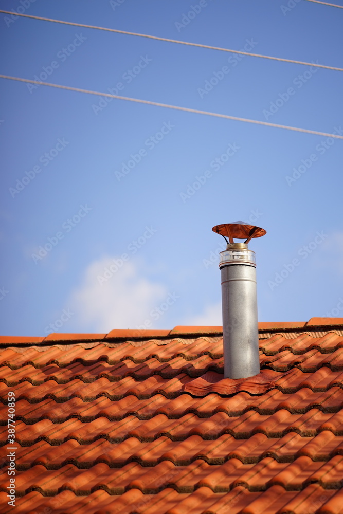 Red tile roof with galvanized chimney chimney against blue sky Red tile roof with galvanized chimney chimney against blue sky