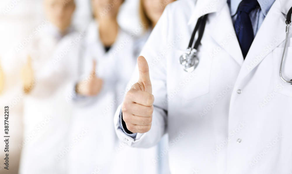 Group of professional doctors are standing as a team with thumbs up in a sunny hospital office, ready to help their patients. Medical help, insurance in health care and medicine concept Group of professional doctors are standing as a team with thumbs up in a sunny hospital office, ready to help their patients. Medical help, insurance in health care and medicine concept