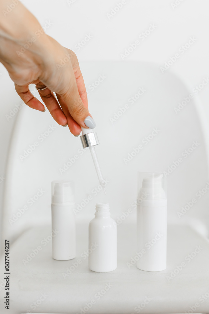 a woman's hand opens a white serum bottle on a white background a woman's hand opens a white serum bottle on a white background