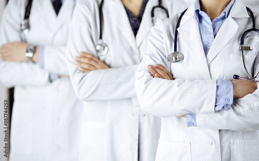 Group of modern doctors standing as a team with arms crossed in hospital office and ready to help patients. Medical help, insurance in health care, best disease treatment and medicine concept Group of modern doctors standing as a team with arms crossed in hospital office and ready to help patients. Medical help, insurance in health care, best disease treatment and medicine concept