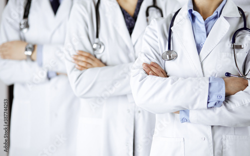 Group of modern doctors standing as a team with arms crossed in hospital office and ready to help patients. Medical help, insurance in health care, best disease treatment and medicine concept