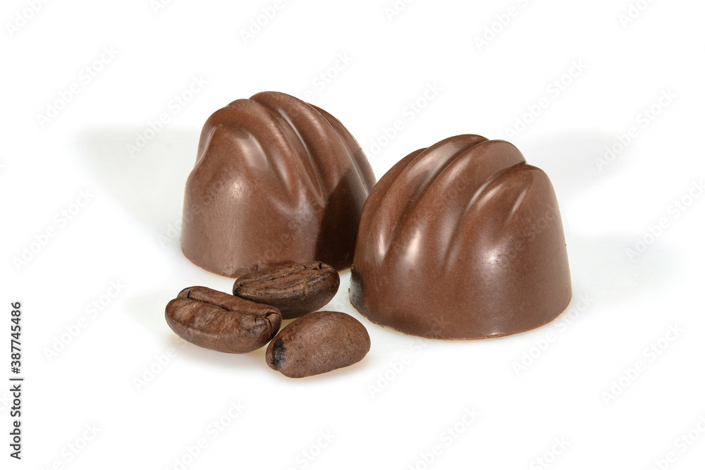 Chocolate pralines and coffee beans. Two dark chocolate bonbons with coffee souffle, macro close up isolated on white background. Chocolate pralines and coffee beans. Two dark chocolate bonbons with coffee souffle, macro close up isolated on white background.