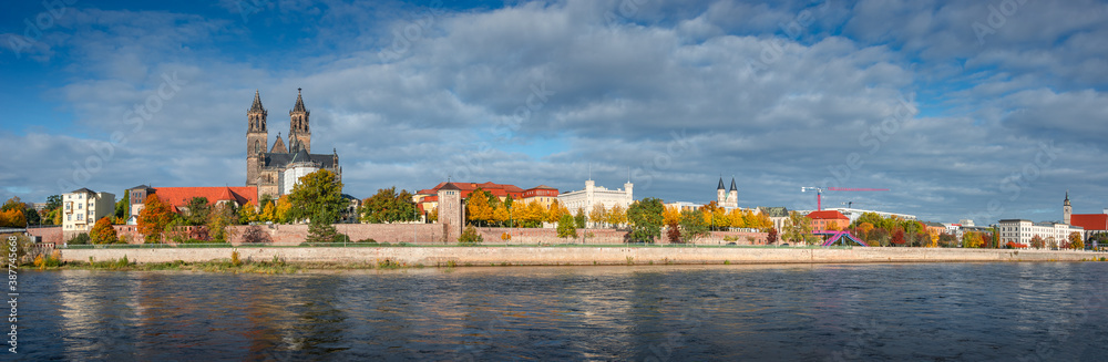 Panoramic view over downtown of Magdeburg, old town, Elbe river and magnificent Cathedral at golden Autumn with dramatic sky but sunny day, Magdeburg, Germany.