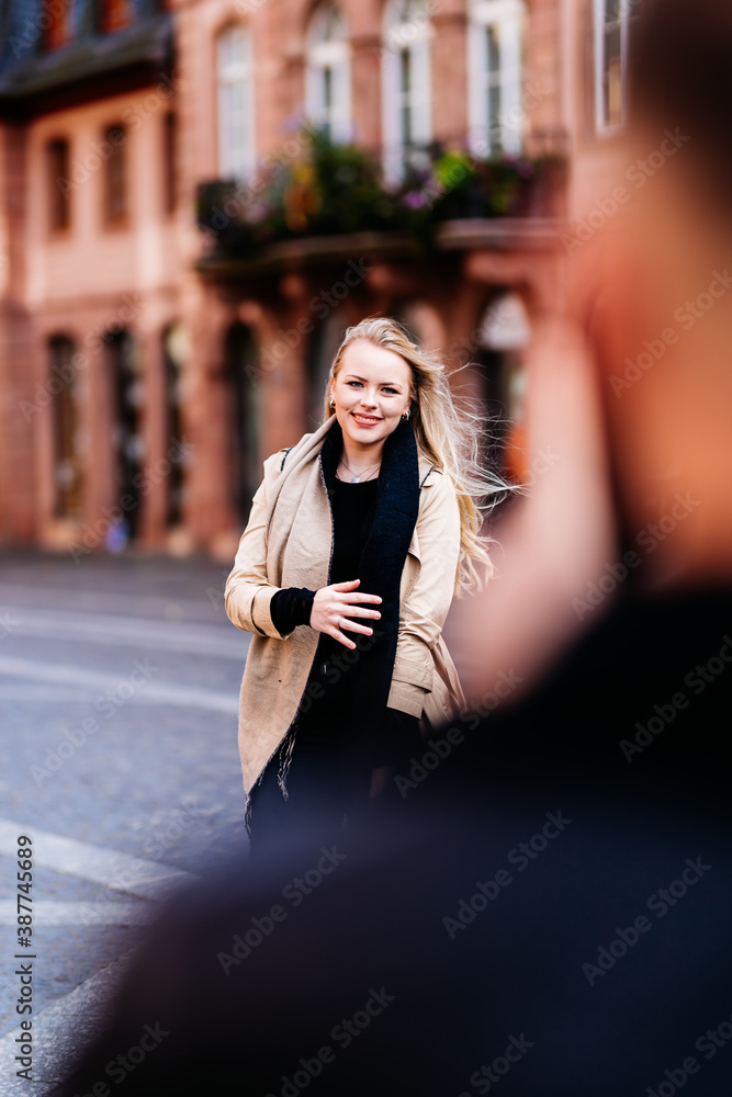 Fototapeta premium Young woman is photographed by her boyfriend with a cell phone and poses