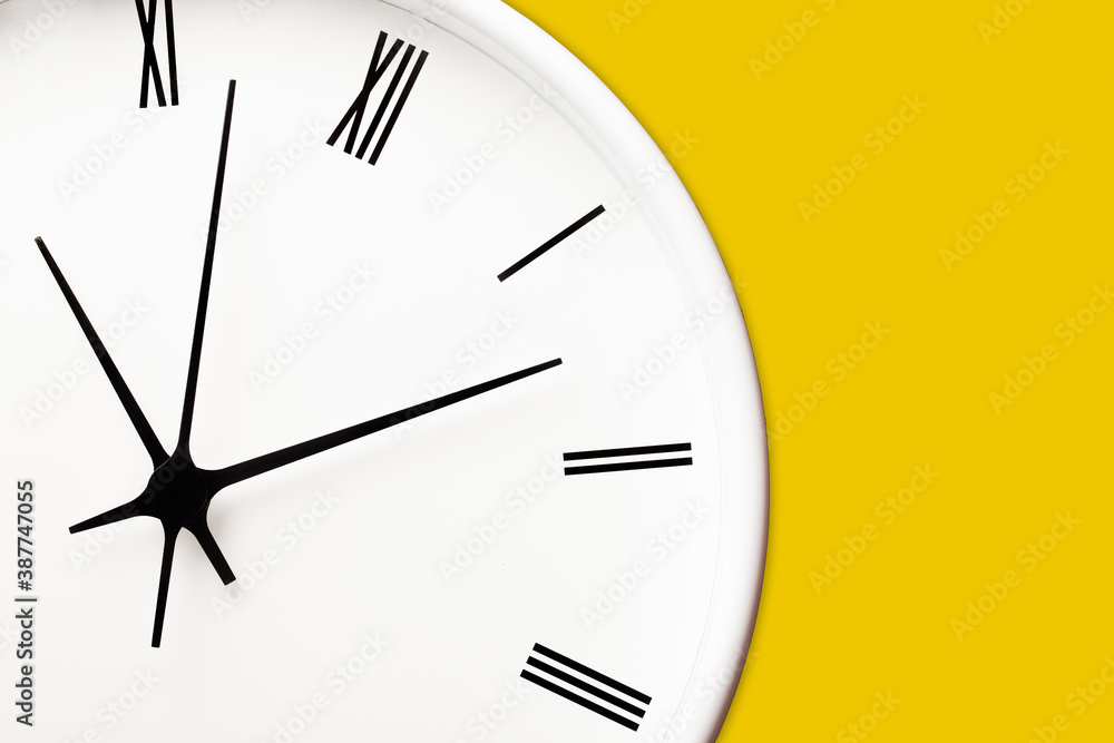 White round clock with black arrows and numbers on yellow wall. Time ...
