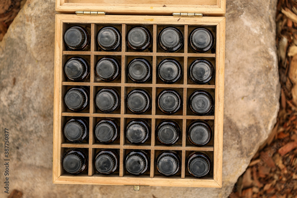 Top view of wooden storage box full of essential oil bottles on rock in outdoor setting Top view of wooden storage box full of essential oil bottles on rock in outdoor setting