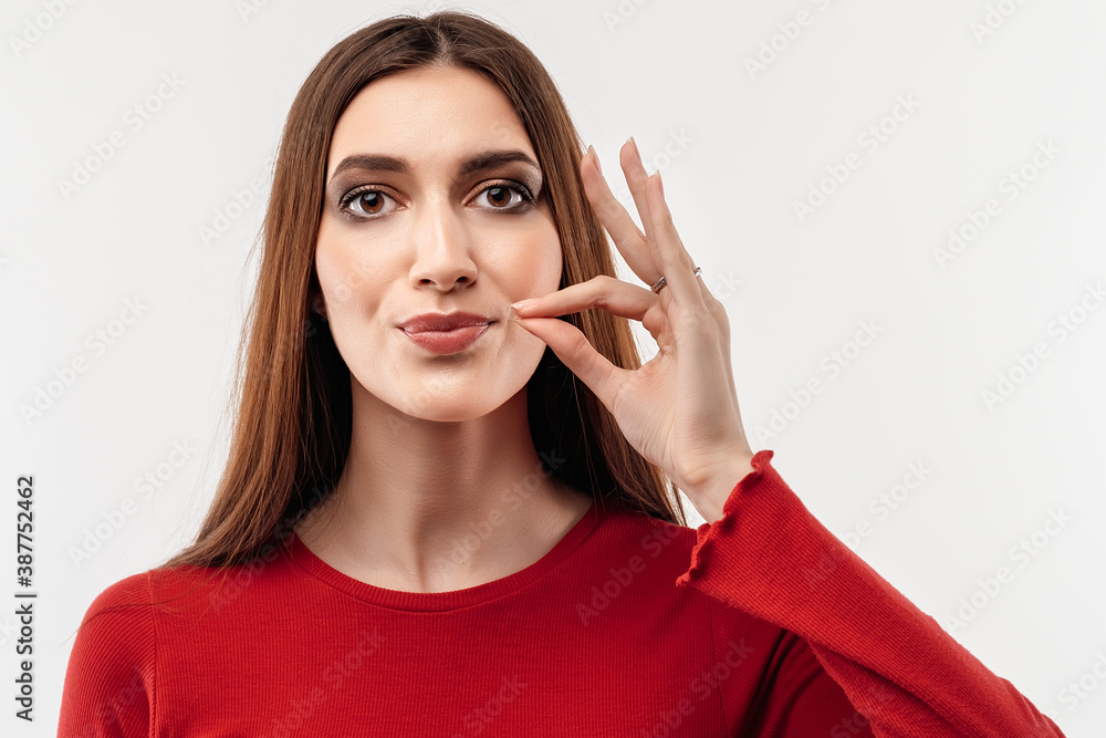 Young woman showing zip gesture as if shutting mouth on key, promises to keep secret. Silence and secret concept