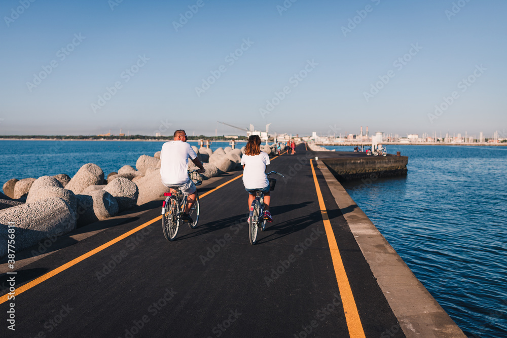 Obraz premium Marina di Ravenna, Ravenna / Italy - August 2020: People riding bicycles on the Zaccagnini pier
