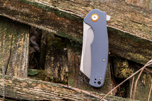 A folded knife with a gray handle on planks outside. photo