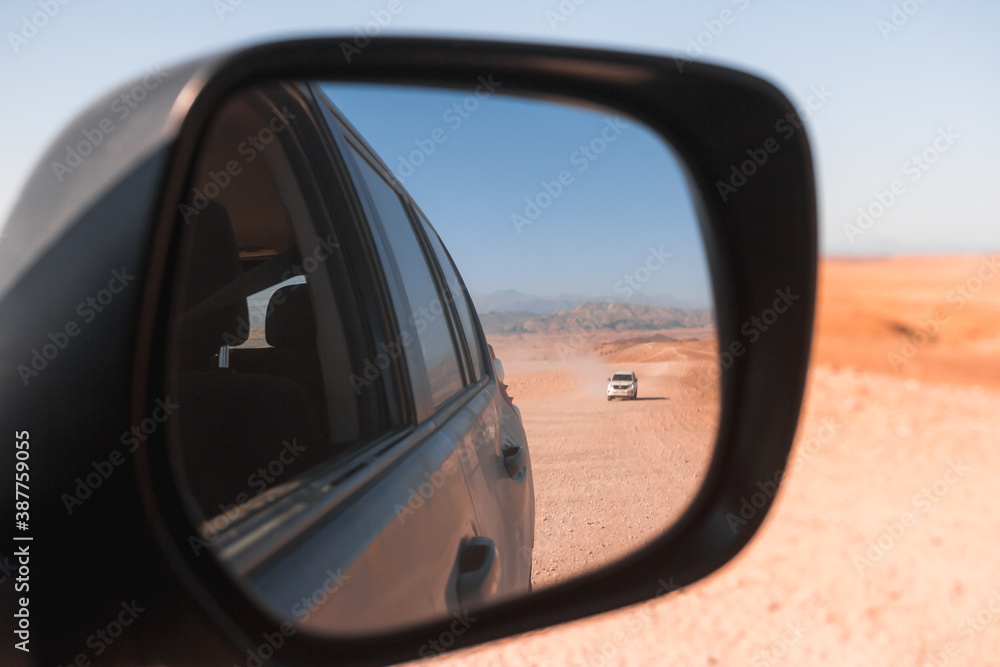Mirror view of 4x4 vehicle in dry mountainous desert area 