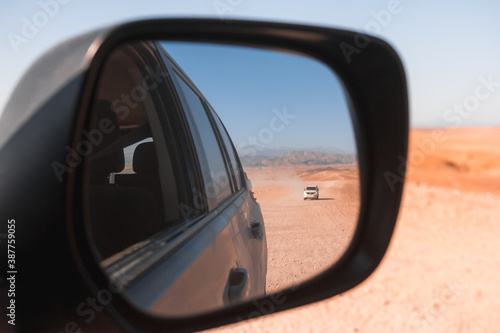 Mirror view of 4x4 vehicle in dry mountainous desert area  © Liam M