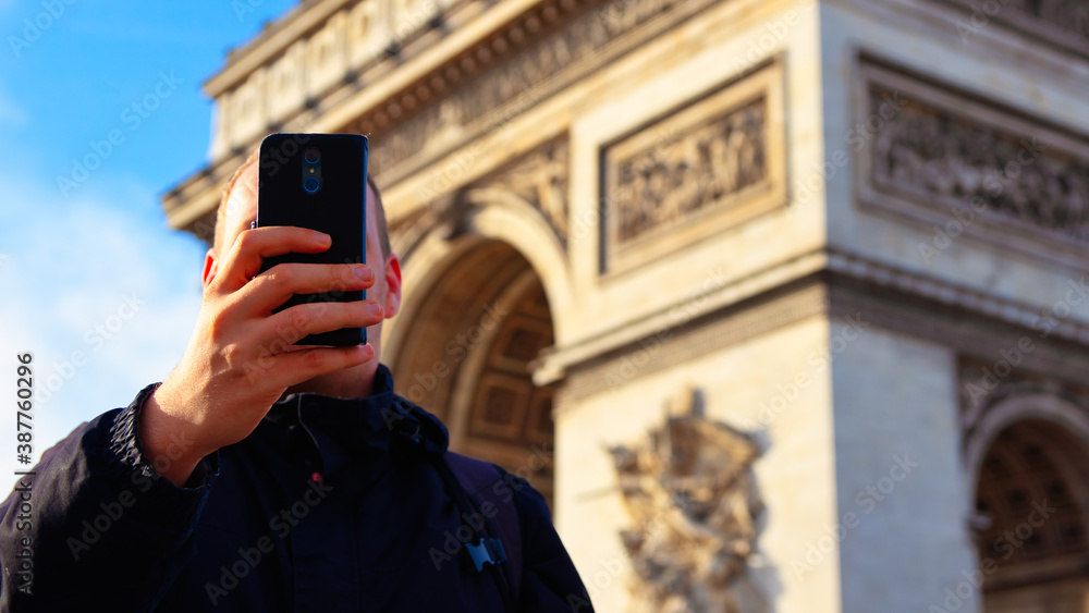 A tourist takes a selfie at the Arc de Triomphe with his cell phone