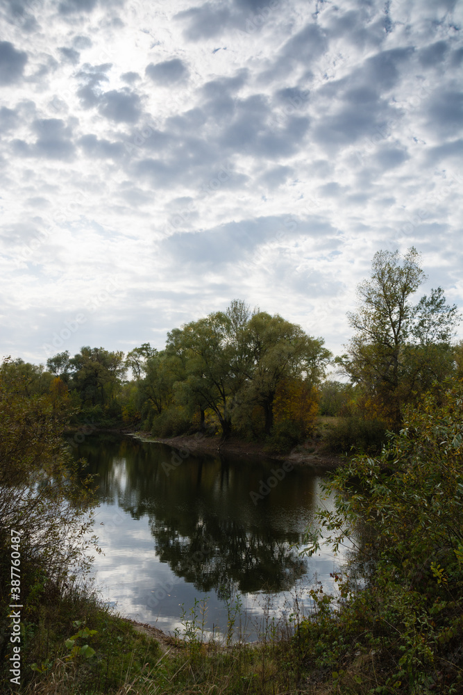 Autumn landscape, lake, shore, trees and cloudy sky Autumn landscape, lake, shore, trees and cloudy sky