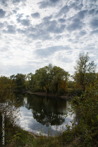 Autumn landscape, lake, shore, trees and cloudy sky