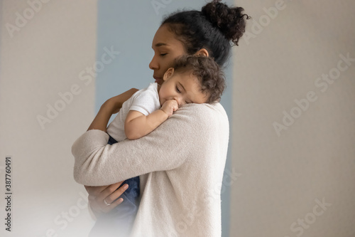 Canvas Print Loving young biracial mother hold in hands embrace small newborn baby child