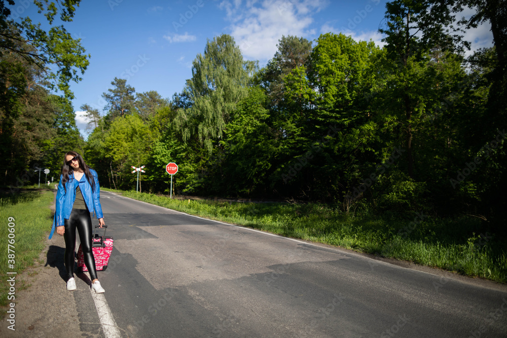 The teenager returns on foot along the asphalt road among lush greenery - wonderful trees and shrubs.