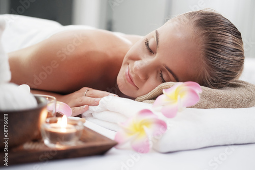 Smiling Caucasian woman in white bath towel lie down and relaxing on bed preparing for massage therapy at alternative medicine healing spa Center in Thailand