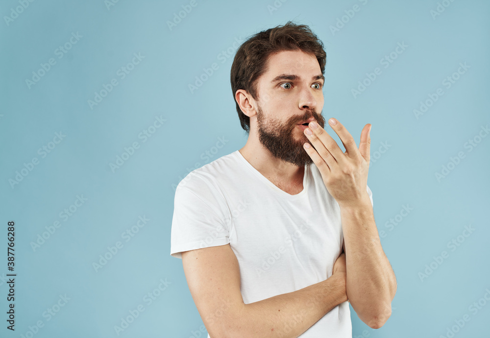 An energetic man gesturing with his hands on a blue background and a thick beard in a white t-shirt An energetic man gesturing with his hands on a blue background and a thick beard in a white t-shirt