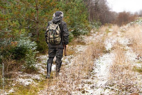 Hunter with a gun and a backpack in the winter forest