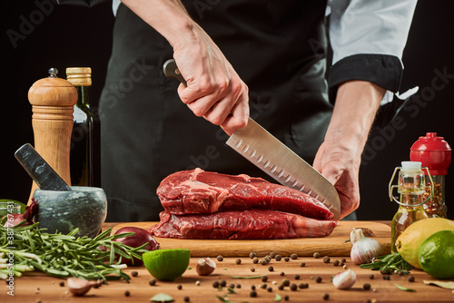 Chef cutting meat with Santoku knife. Seasoning and condiments photo